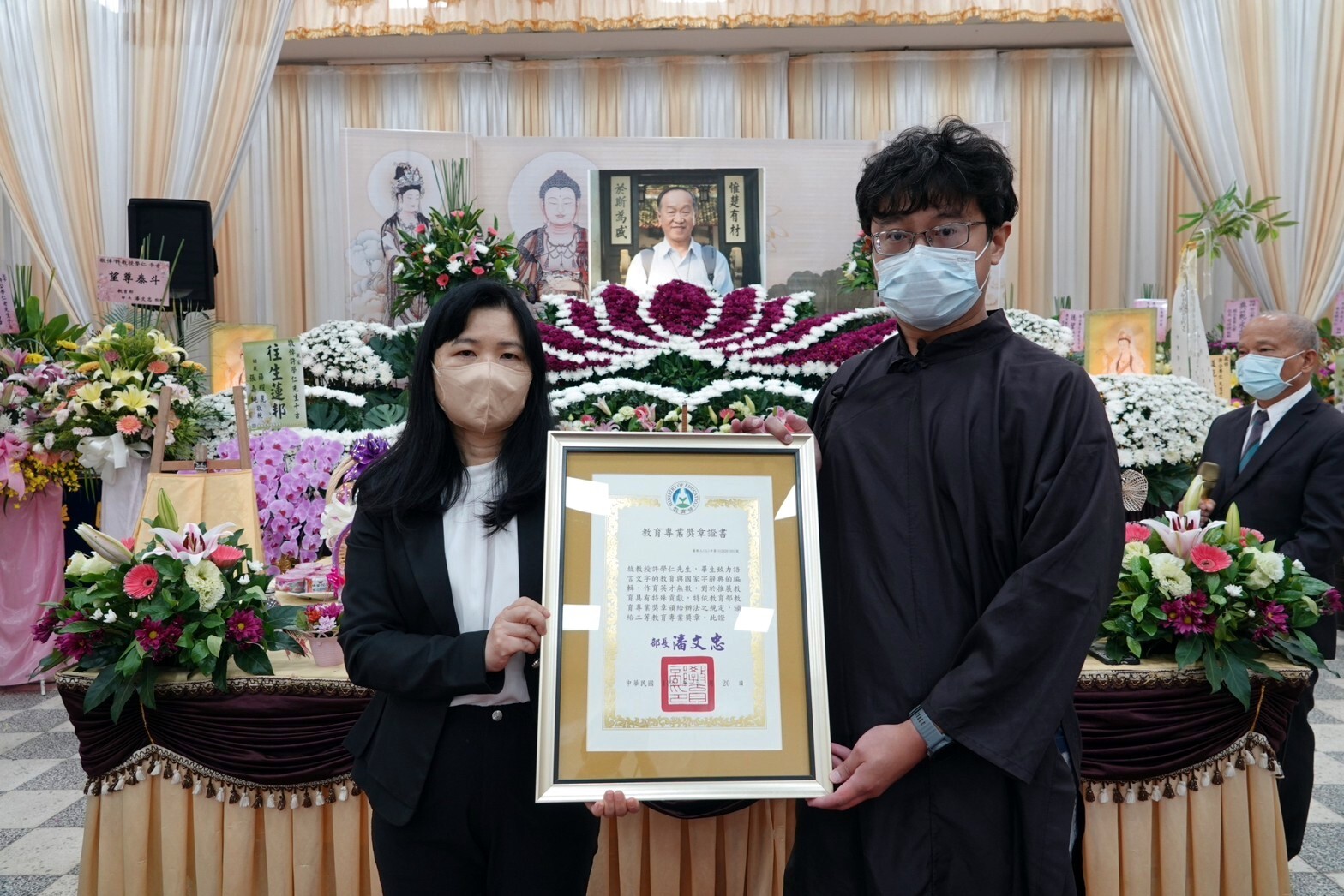 教育部終身教育司李毓娟司長頒給獎章證書,由許故教授公子許庭瑋先生接受