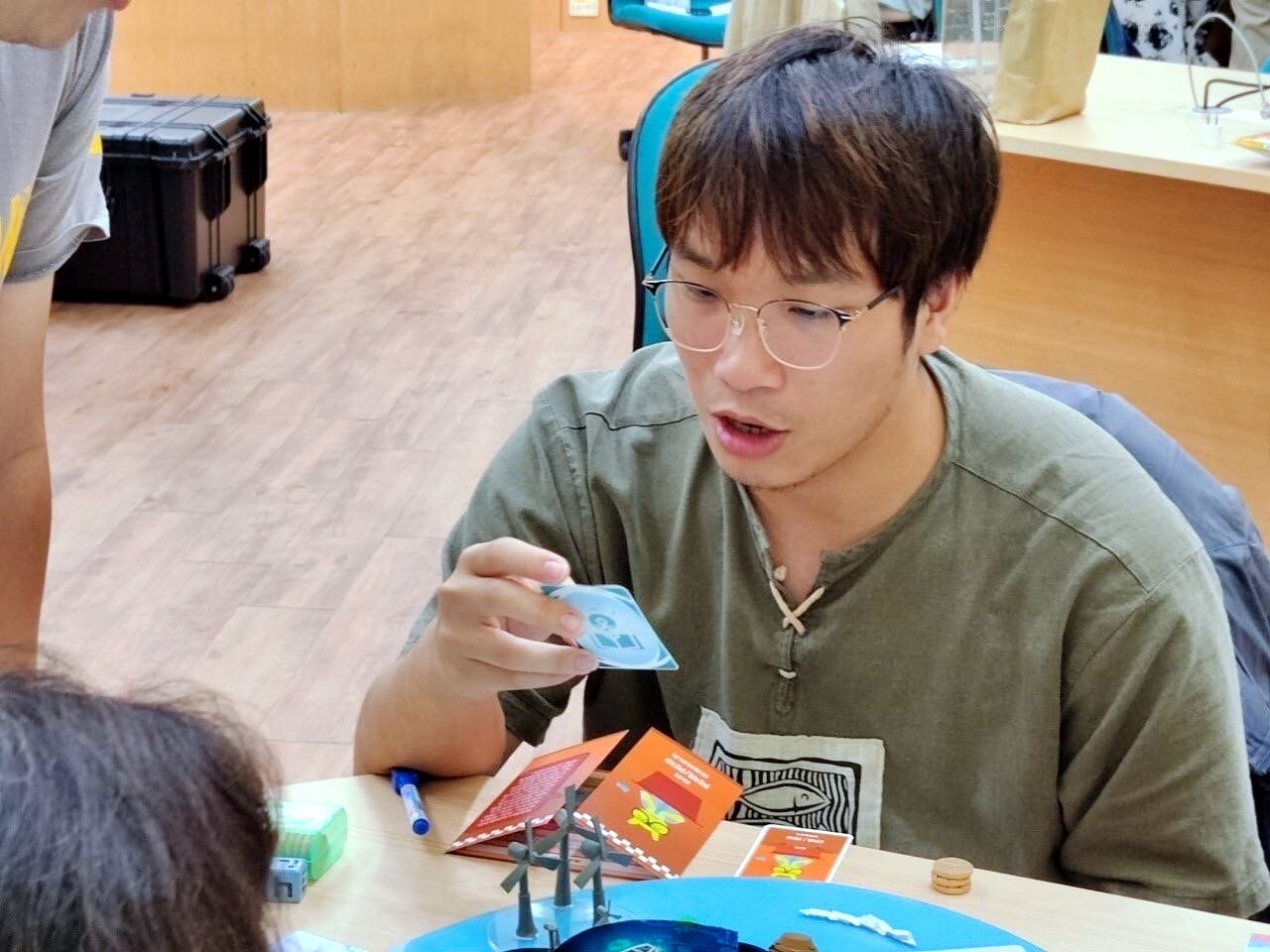 桌遊遊玩過程,參與同學正在念誦遊戲事件卡的內容