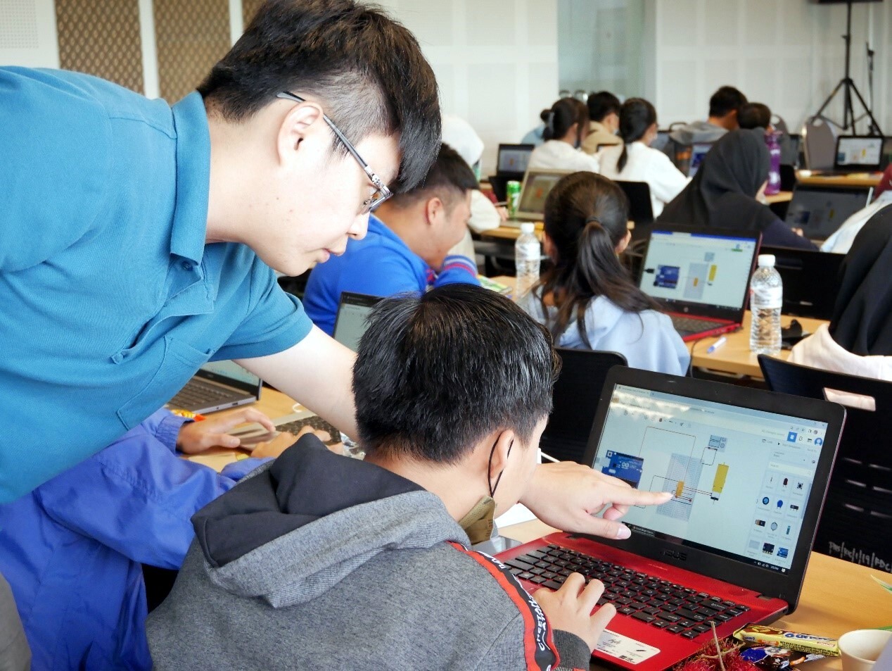 學生於電腦上操作模擬開發版,簡暐哲老師細心指導