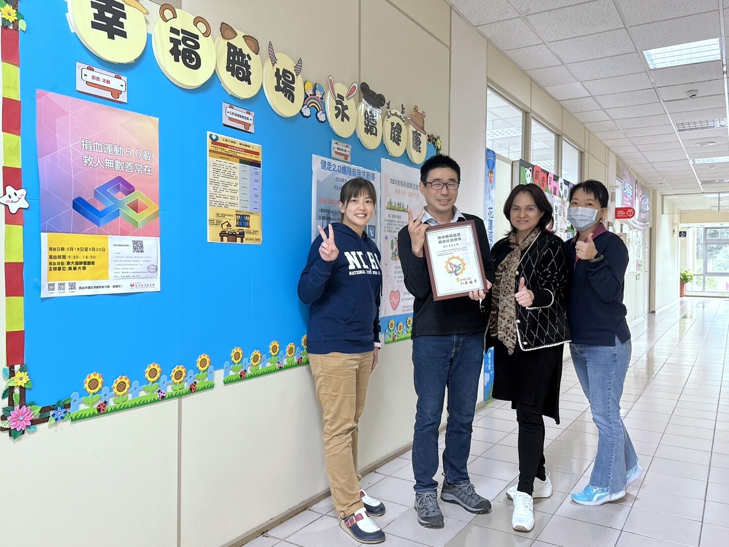 學務處衛生保健組黎士鳴組長與同仁開心展示「健康職場認證標章」證書
