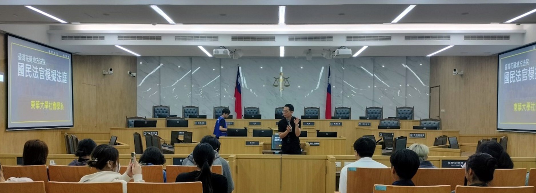 花蓮地方法院吳明駿庭長(中間站立者)在設備完善的國民法官法庭對師生做解說