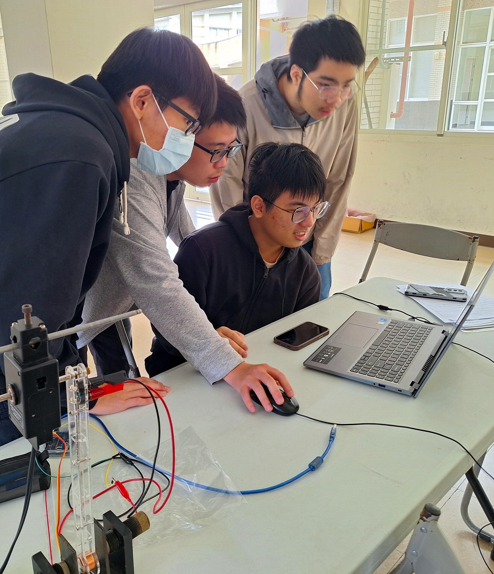 助教仔細指導學生,利用電腦擷取實驗數據及分析