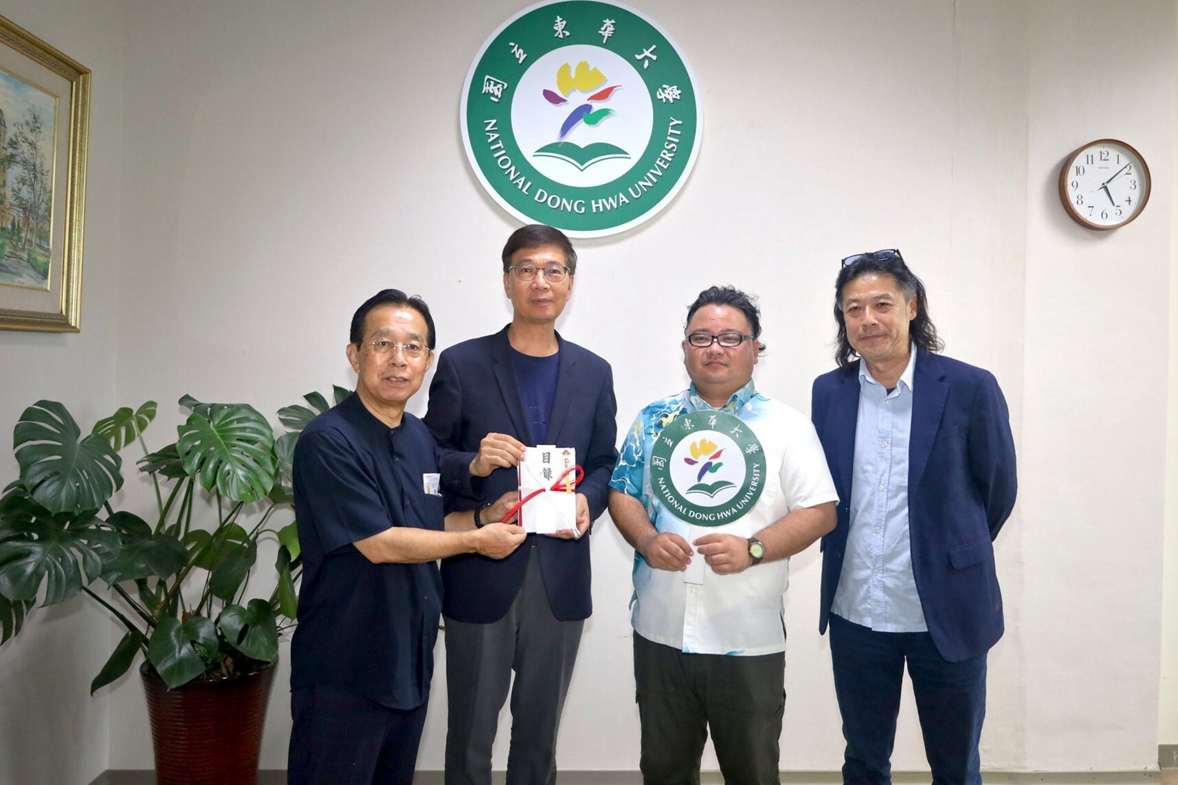 日本琉台文化交流協會比嘉伸雄理事長(左一)在臺灣友人音樂老師周恭平先生(右一)陪同下捐贈東華大學50萬元日幣