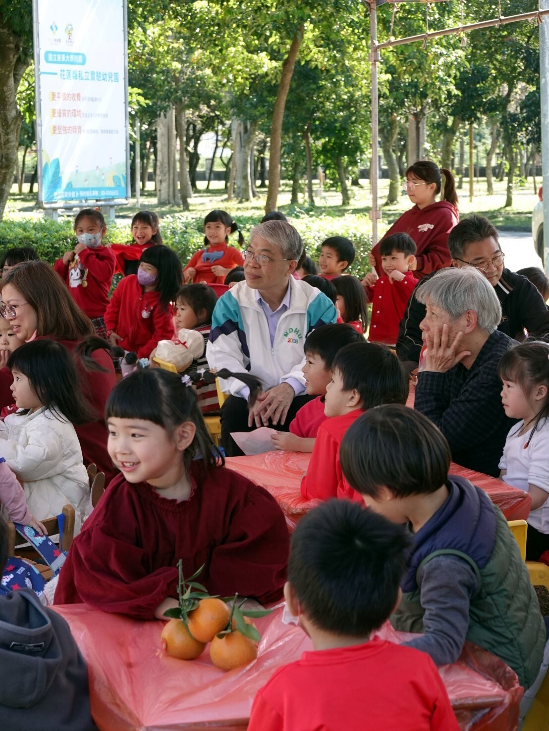 師生圍坐紅桌共享表演時光,紅色桌巾營造辦桌般的熱鬧氣息,現場充滿歡笑與祝福